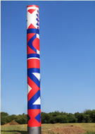 Colonne peinte de motifs rouges, blancs et bleus, dressée dans l'herbe