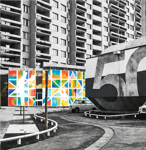 Façade d'immeuble en noir et blanc, panneaux peints de carrés colorés au premier plan
